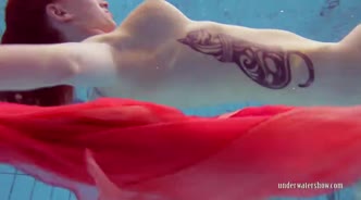 Рыжеволосая девушка с тату на теле плавает голая в бассейне